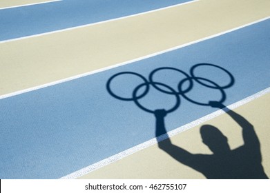 NEW YORK CITY - JUNE 1, 2016: Shadow of an athlete holds Olympic rings on the lanes of a blue and tan running track.