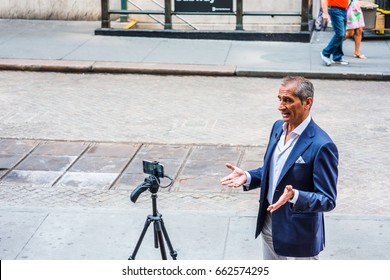 NEW YORK CITY - JUNE 10, 2017: Foreign, Non-English Speaking Old Man Travels, Visits New York, Self Video Recording With Cell Phone, Tripod, Standing On Street Outside New York Stock Exchange, Speaks.