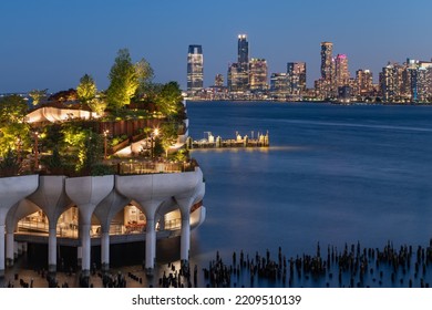 New York City, Little Island public park in evening with view of Downtown Jersey City. Elevated park in the Meatpacking District at Hudson River Park (Pier 55), West Village, Manhattan