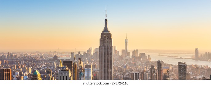 New York City. Manhattan downtown skyline with illuminated Empire State Building and skyscrapers at sunset. Panoramic composition.