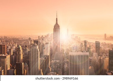 New York City. Manhattan Downtown Skyline With Illuminated Empire State Building And Skyscrapers At Sunset. Vertical Composition. Warm Evening Colors. Sunbeams And Lens Flare.