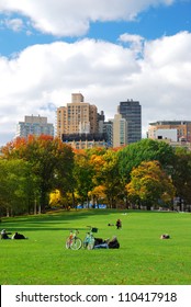 New York City Manhattan Skyline Panorama Viewed From Central Park With Cloud And Blue Sky And People In Lawn.