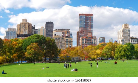 New York City Manhattan skyline panorama viewed from Central Park with cloud and blue sky and people in lawn. 