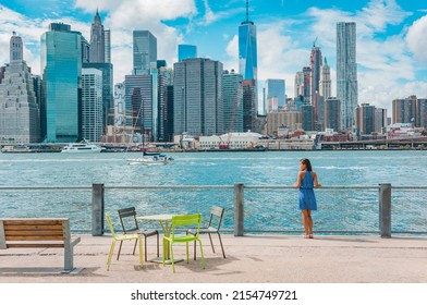 New York city Manhattan skyline seen from Brooklyn waterfront - woman enjoying view. American people walking enjoying view of Manhattan over the Hudson river from the Brooklyn side. NYC cityscape
