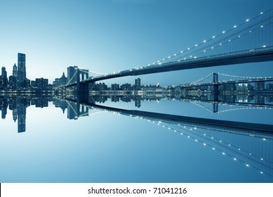 New York City Manhattan skyline and Brooklyn Bridge at dusk with reflection