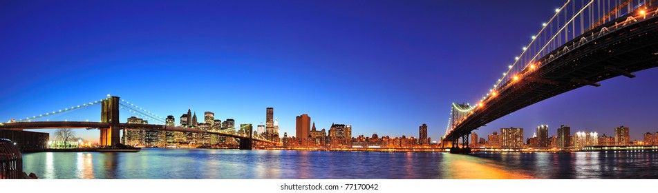 New York City Manhattan skyline panorama with Brooklyn Bridge and Manhattan Bridge over East River at dusk illuminated with reflections and downtown skyscrapers viewed from Brooklyn.