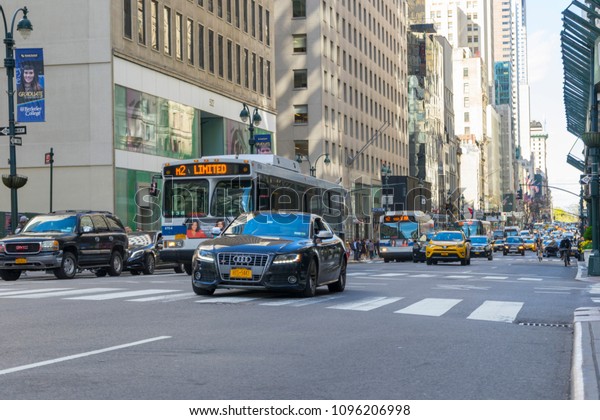 New York City, NY - April 26,2018 : Many cars commute on\
5th Ave. with building in the background in New York City, NY on\
April 26,2018. 
