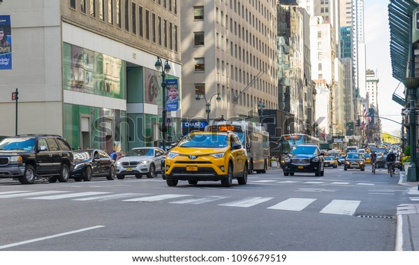 New York City, NY - April 26,2018 : Many cars commute on\
5th Ave. with building in the background in New York City, NY on\
April 26,2018. 