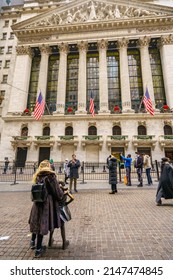 NEW YORK CITY, NY - December 28, 2021: Vertical View Of New York Stock Exchange Building And Tourists Taking Pictures With The Bronze Sculpture 'Fearless Girl'.