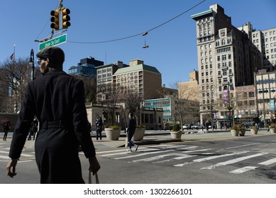 New York City, NY - March 11, 2018: Shoes Hang From A Telephone Wire Above A Pedestrian Crossing In Union Square As People Cross The Street.