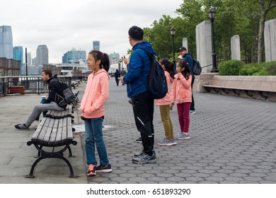 New York City, NY, May 30, 2017: Family In Matching Hoodies Pauses In Battery Park To Gaze At The Statue Of Liberty In The Distant.