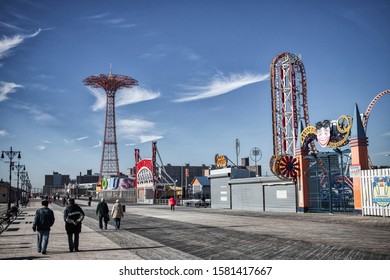 New York City, NY - Novermber 18, 2019: Unidentified people walking the walkway on the beach near the Luna Park amusement park in Coney Island in Brooklyn, NY 