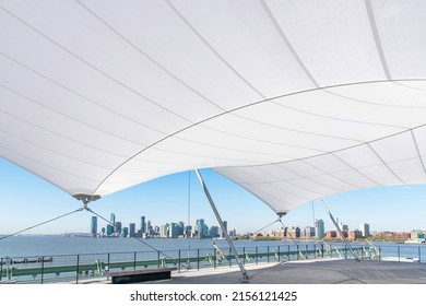 New York City, NY, USA-May 2022; Panoramic view of the waterfront of Jersey City with its skyscrapers seen from under large white canopy that covers part of Pier 57 Rooftop Park 