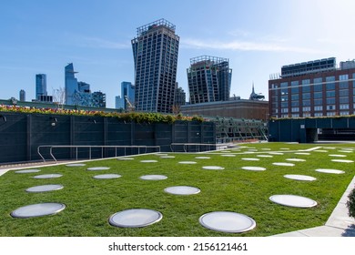 New York City, NY, USA-May 2022; Low angle view from the grass on Rooftop Park of Pier 57 towards the city with Empire State building, The XI building and the Edge in Hudson Yards