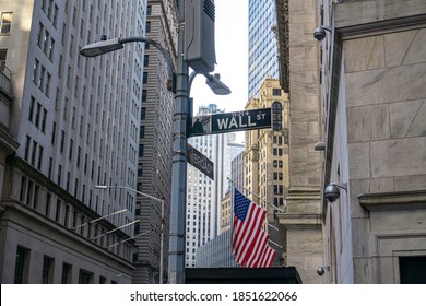 New York City, NY/USA - November 8 2020: Road Sign Of New York Wall Street At The Corner Broad Street. American Flag Hanging From The New York Stock Exchange Building