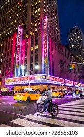 NEW YORK CITY - SEPTEMBER 28, 2017:  View Of Radio City Music Hall In Manhattan Seen At Night With Lights, Cars, Taxi's, Cyclist And Harry Styles On Marquee. 