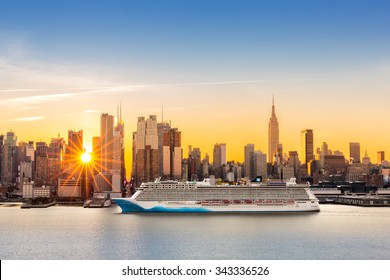 New York City Skyline At Sunrise, As Viewed From Weehawken, Along The 42nd Street Canyon. A Large Cruise Ship Sails Hudson River, While Sun Beams Burst Between The Skyscrapers.