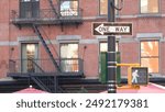 New York City street crossroad, yellow traffic light, oneway transport road intersection, United States. Residential building architecture. Red brick, brown stone. Real estate. One way arrow road sign