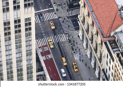 New York City Street With Yellow Taxis And People Walking. Cabs, Cars And Pedestrians Crossing Crosswalk. Busy NYC Downtown Traffic. Aerial View From Above.