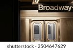 New York City subway station interior, underground metropolitan platform sign. Metro railway train, passenger public transport, United States. Text signboard: Broadway. NYC Midtown, Manhattan traffic.