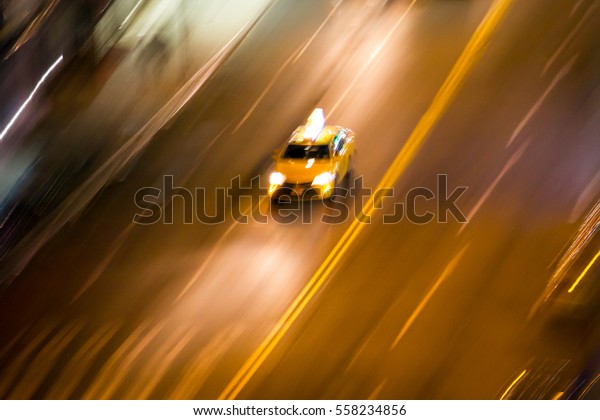 New York City taxi driving fast on city\
street at night blurred background\
NYC