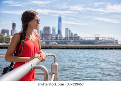 New York City travel - Tourist woman on summer travel looking at waterfront view of skyline with one tower building in the background. 