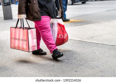New York City, USA - April 6, 2018: Manhattan NYC Sidewalk In Midtown On 6th Avenue Road And Closeup Of Walking Woman Carrying Pink Victorias Secret And JCPenney Bag