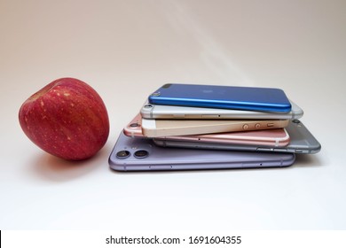 New York CITY / USA - April 2, 2020: Apple IPhones Stacked With A Real Apple Fruit Next To Them. White Backdrop. 