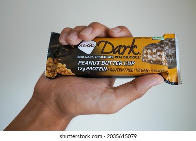 New York City, New York  USA - July 15, 2021: A Hand Holding A Peanut Butter Cup NuGo Dark Protein Bar.