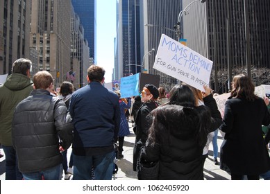 New York City, New York / USA - March 24 2018: A protester on 6th Avenue carries a sign saying, "Moms Demand Action For Gun Sense In America" during the March for Our Lives in New York City.