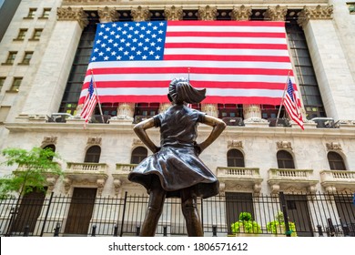 NEW YORK CITY, USA - MARCH 15, 2020:  Fearless Girl Statue looking up at  New York Stock Exchange building at Wall Street in Manhattan, New York City, USA