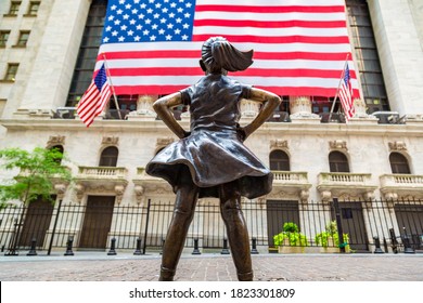 NEW YORK CITY, USA - MARCH 15, 2020:  Fearless Girl Statue Looking Up At  New York Stock Exchange Building At Wall Street In Manhattan, New York City, USA