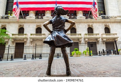 NEW YORK CITY, USA - MARCH 15, 2020:  Fearless Girl Statue Looking Up At  New York Stock Exchange Building At Wall Street In Manhattan, New York City, USA