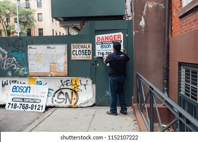 New York City, USA - May, 2017 NYC Street Photography. A Construction Worker Is Detaching A Danger Sign In West Village