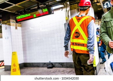 New York City, USA - October 29, 2017: Employee Worker Inspecting Leak In Underground Transit Empty Large Platform In NYC Subway Station, Wet Floor Sign Slippery Yellow Cone