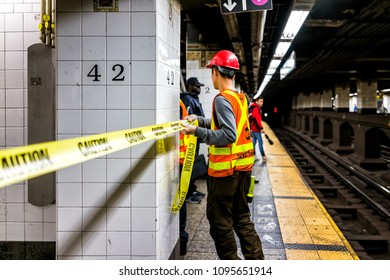 New York City, USA - October 29, 2017: Employee Worker Wrapping Caution Tape, Inspecting Leak In Underground Transit Empty Large Platform In NYC Subway Station In Grand Central