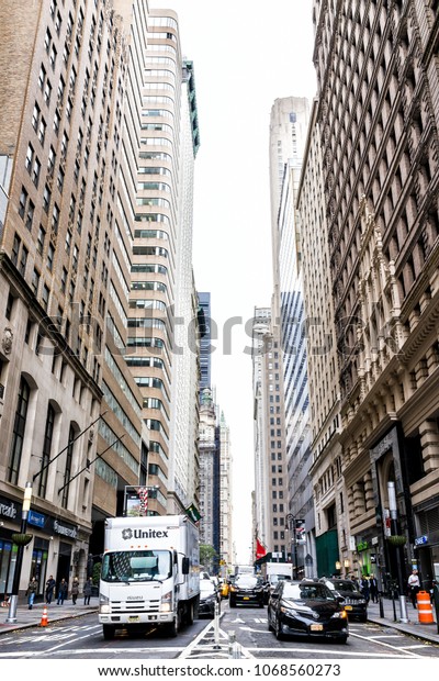 New York City, USA -\
October 30, 2017: Broadway St by Wall Street stock exchange\
Charging Bull people crossing in NYC Manhattan lower financial\
district downtown, NYSE