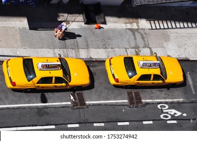 New York City, USA-August 2019: High Angle View Of A Number Of  Yellow Cabs Parked On The Side Of The Road Between Sidewalk And Bicycle Lane