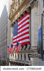 New York City, USA-October 2009; Side View Of The Facade Of The New York Stock Exchange (NYSE) Covered In A Giant American Flag; Street Sign Wall Street In Foreground