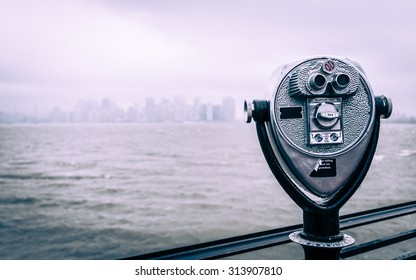 New York City Viewfinder Binoculars. A Traditional Tourist Viewfinder On Liberty Island Looking Towards The NYC Skyline On A Grey And Overcast Day.