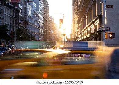 New York City yellow taxi cabs speeding through the intersection of 23rd Street and 5th Avenue with sunlight shining between the background buildings in Midtown Manhattan NYC - Powered by Shutterstock