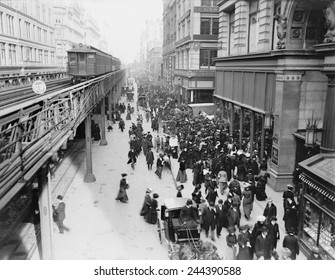 New York City's Sixth Avenue Crowded With Shoppers In 1903. Horse Drawn Carriages And Wagons Travel On The Street Level As An Elevated Train Passes Above.