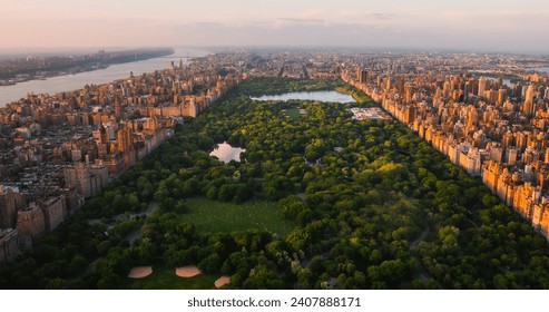 New York Cityscape at Sunset. Aerial Shot from a Helicopter. Modern Skyscraper Buildings Around Central Park in Manhattan Island. Focus on Nature, Trees and Lakes in the Park in the City - Powered by Shutterstock