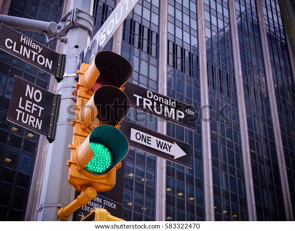 NEW YORK, JAN,20, 2017: NYC Wall street yellow\
traffic light black fake pointer guide One way green light to\
Donald Trump, 45th USA american president, No turn to Hillary\
Clinton policy. Politics