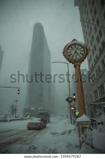 New\
York, New York - JANUARY 5, 2021: A blizzard rips through midtown\
Manhattan on a winter day as cars pass through 5th avenue. The\
flatiron building can be seen in the background.\
