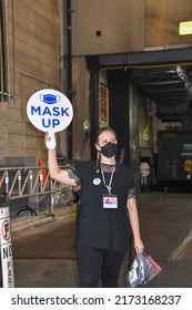 New York, New York - June, 2022: A Woman Wearing A Black Face Mask Is Holding A Round Sign That Says Mask Up Outside A Broadway Theater