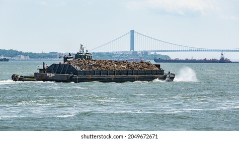 New York, June 30, 2014 - New York Harbor - Barge Filled With Scrap Metal Sailing on the East River.