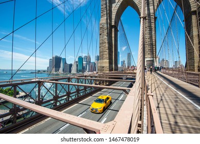 New York Manhattan skyline from the Brooklyn Bridge with yellow taxi
