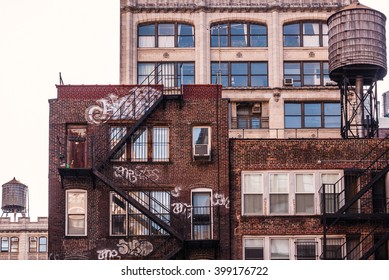 NEW YORK, NEW YORK - MAR 3:  Residential dwellings, with graffiti, in New York City, and also water tank atop the walk-up on March 3, 2012. Many of NYC's residential buildings are pre-war structures.