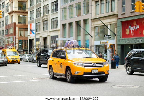 NEW YORK - MARCH 16, 2015: Yellow taxi cabs and\
people rushing on busy streets of downtown Manhattan. Taxicabs with\
their distinctive yellow paint are a widely recognized icon of New\
York City.